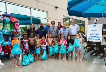 Children posing with PoolCorp for a photo showing the $95,000 donor check