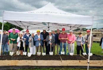 YMCA and local leadership posing with shovels in garden beds filled with dirt