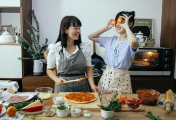 Two individuals making pizza in the kitchen 