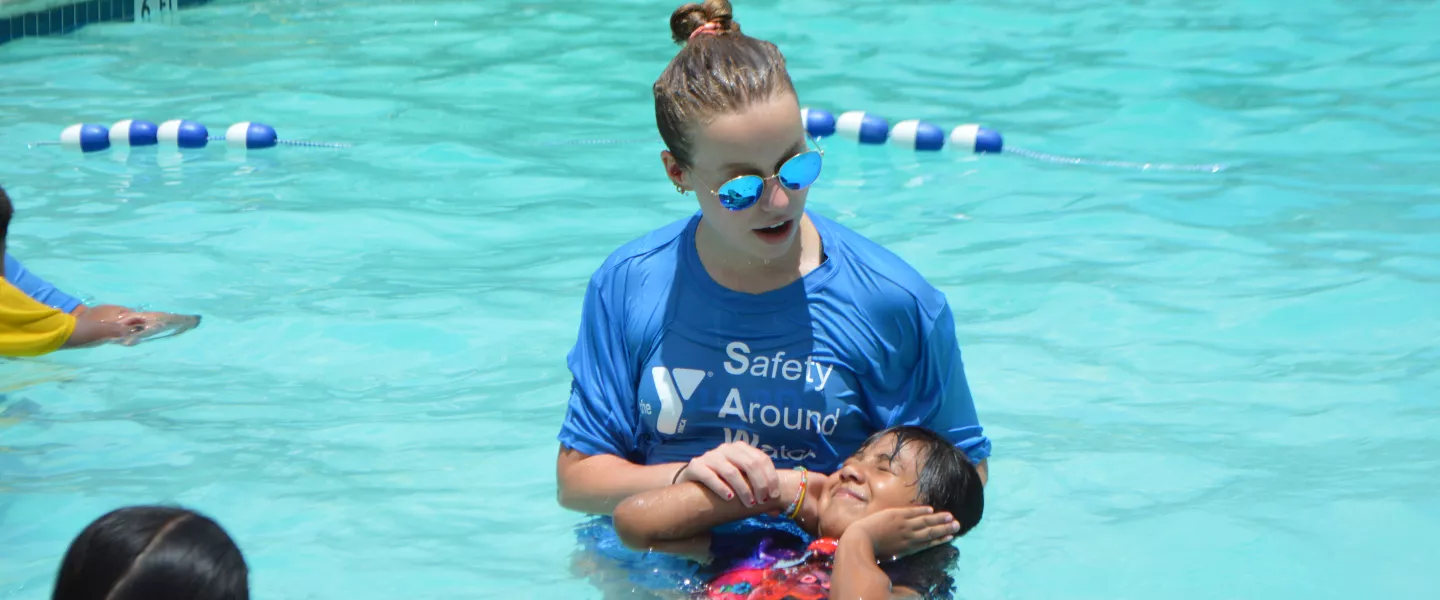 woman giving a little girl swim lessons