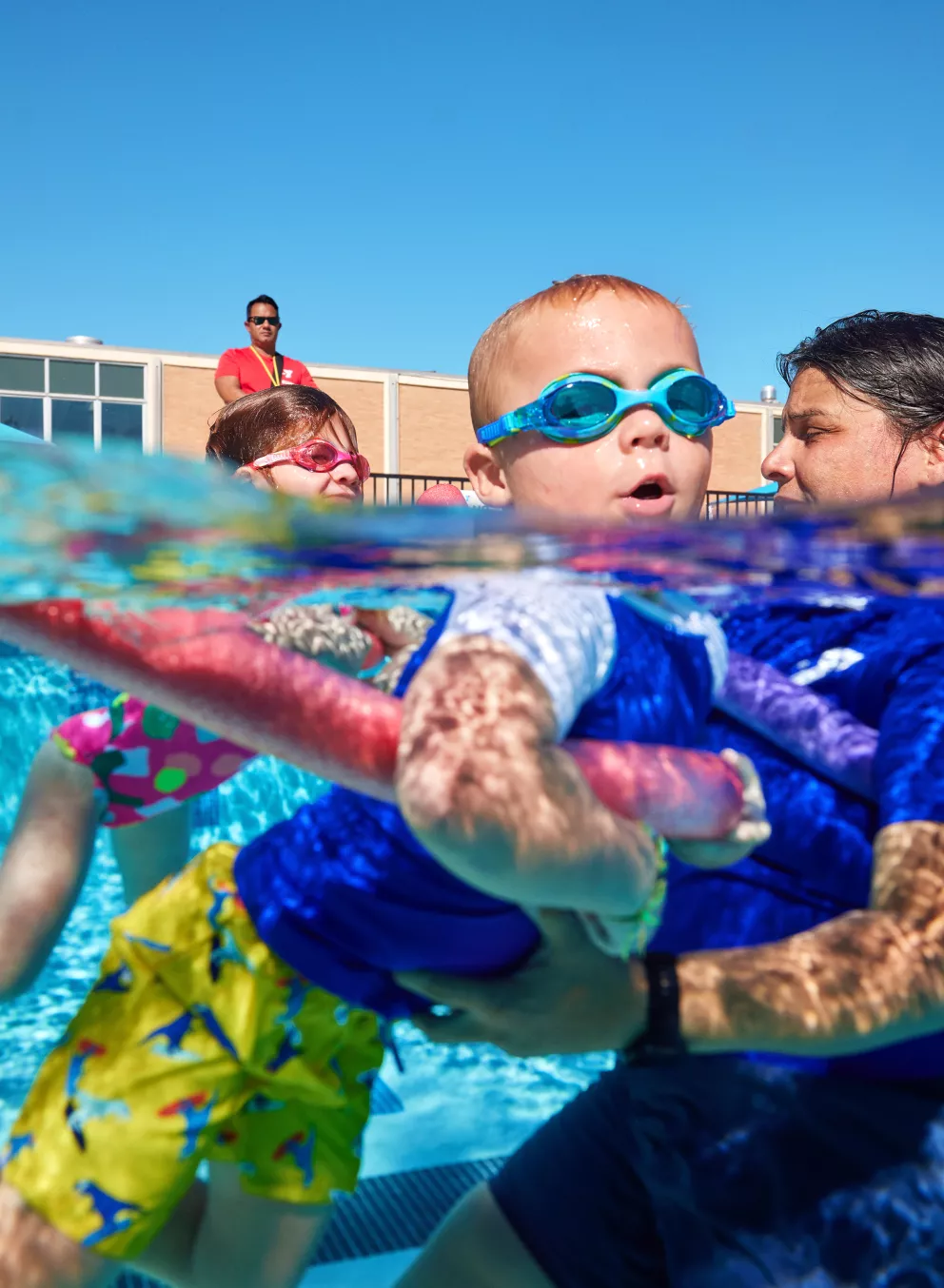Swim instructor with kid and noodle for lessons