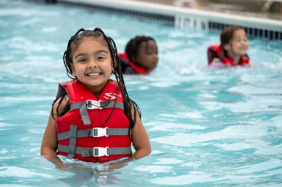 Little girl in the pool with a life jacket on