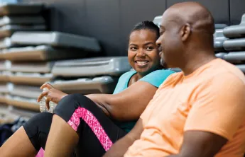 Man and woman sitting down and chatting in a group exercise room