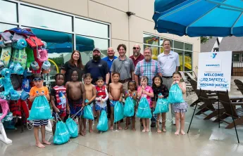 Children posing with PoolCorp for a photo showing the $95,000 donor check
