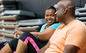 Man and woman sitting down and chatting in a group exercise room
