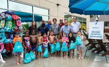Children posing with PoolCorp for a photo showing the $95,000 donor check