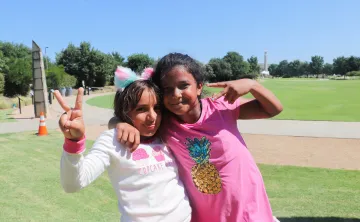 Two girls posting with a peace sign, with the arms around each other